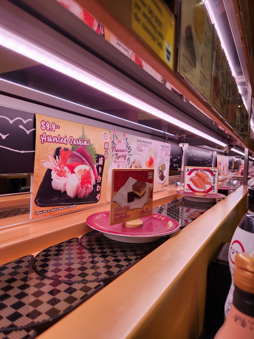 Interior view of a sushi restaurant with a conveyor belt and food displays.