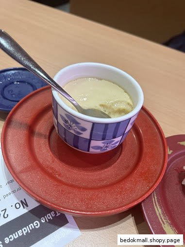 A bowl of chawanmushi or custard with a spoon on a red plate.