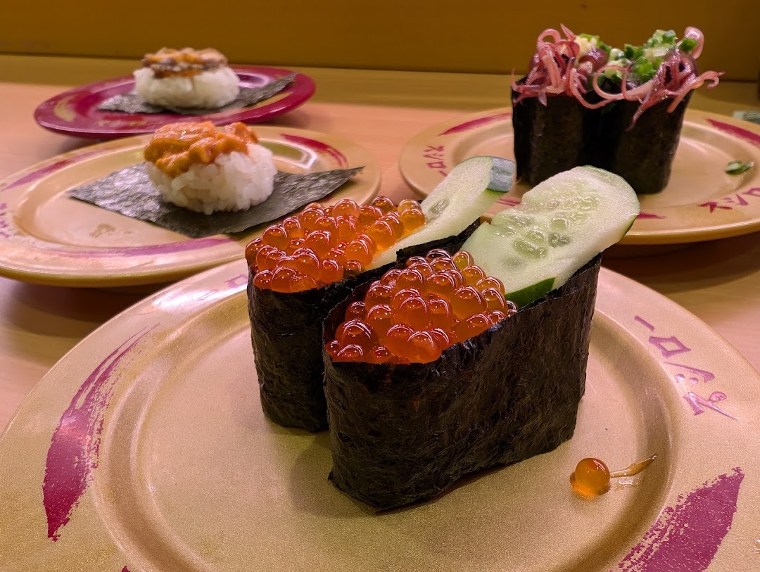 Close-up of various sushi dishes on plates in a restaurant setting.