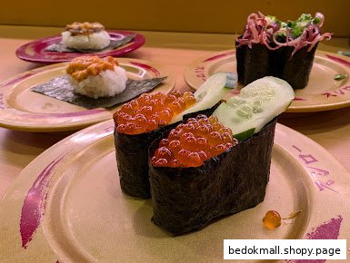 Various sushi dishes, including ikura gunkan maki, on plates.