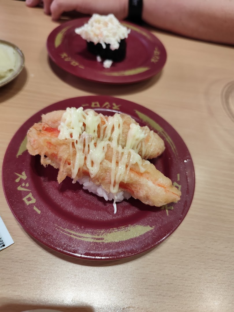Two plates of sushi, one with tempura and mayonnaise, on a wooden table.