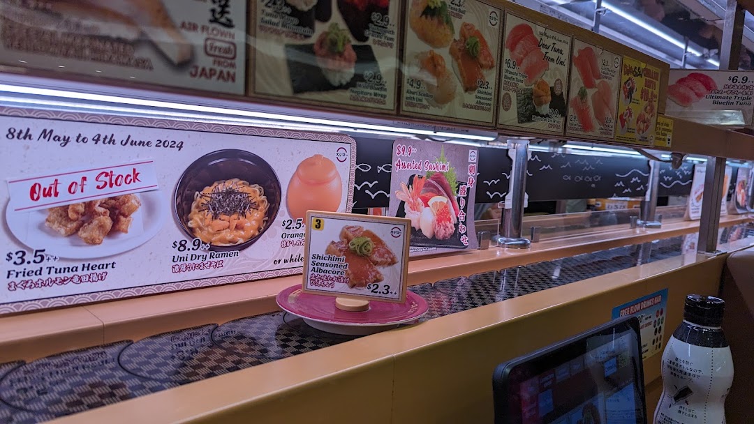 Interior of a sushi restaurant with a conveyor belt and menu displays.