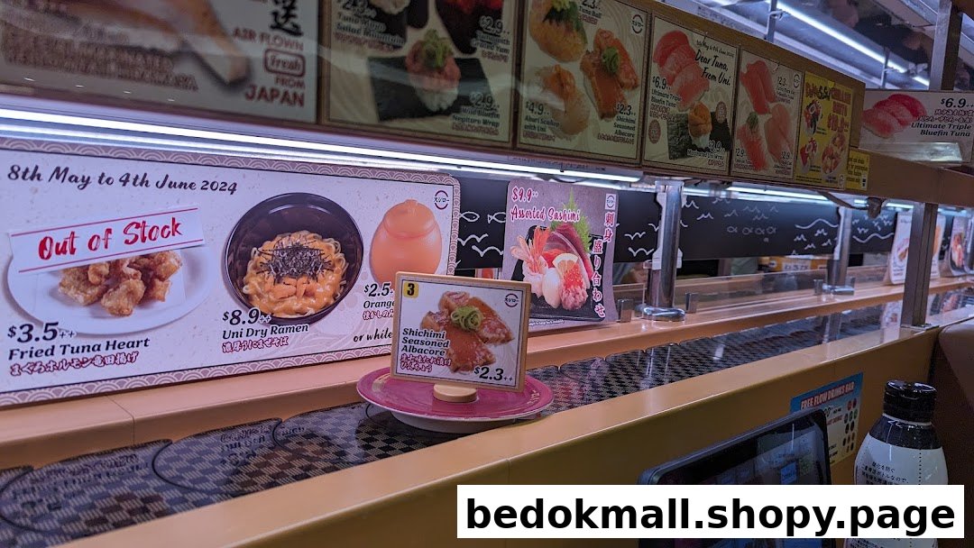 Interior of a sushi restaurant with a conveyor belt and menu displays.