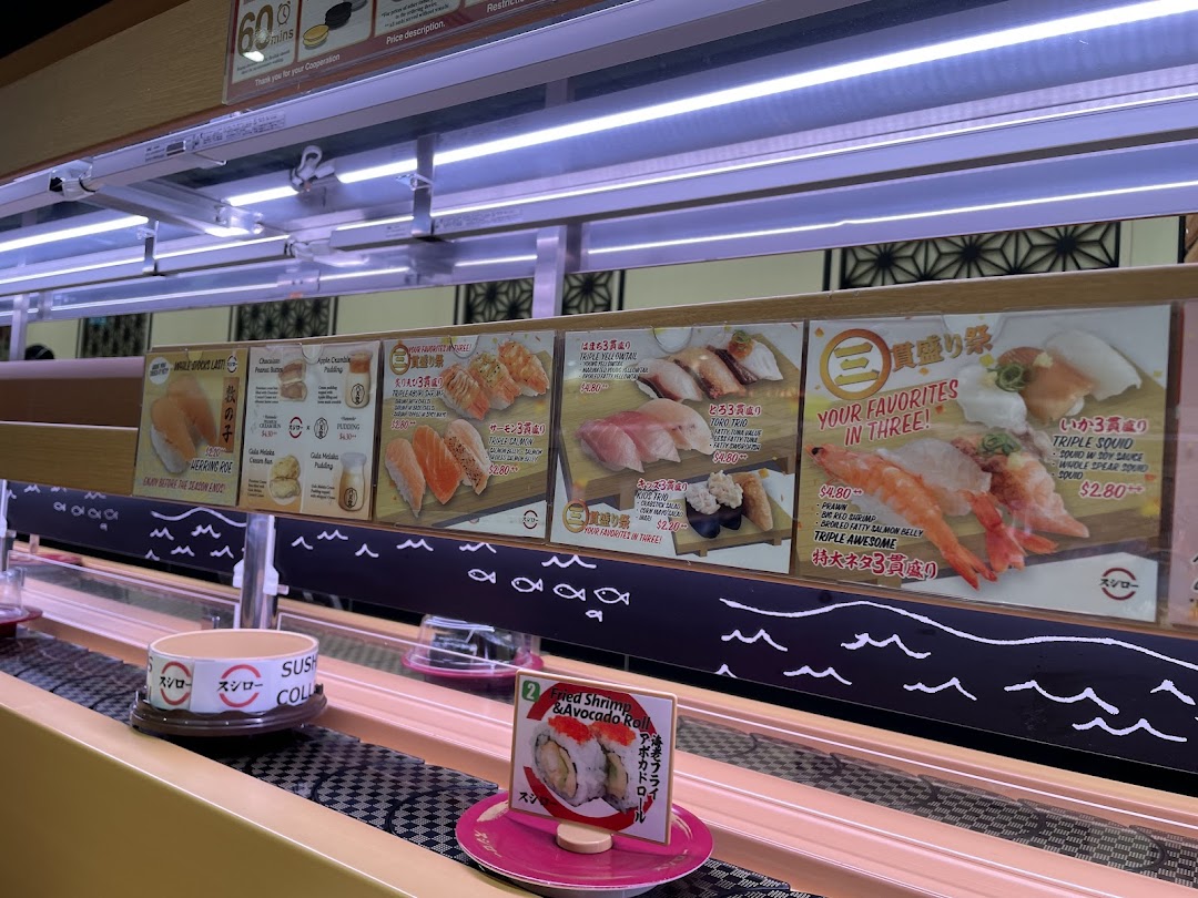 Sushi restaurant interior with conveyor belt and overhead menu displays showing various dishes.