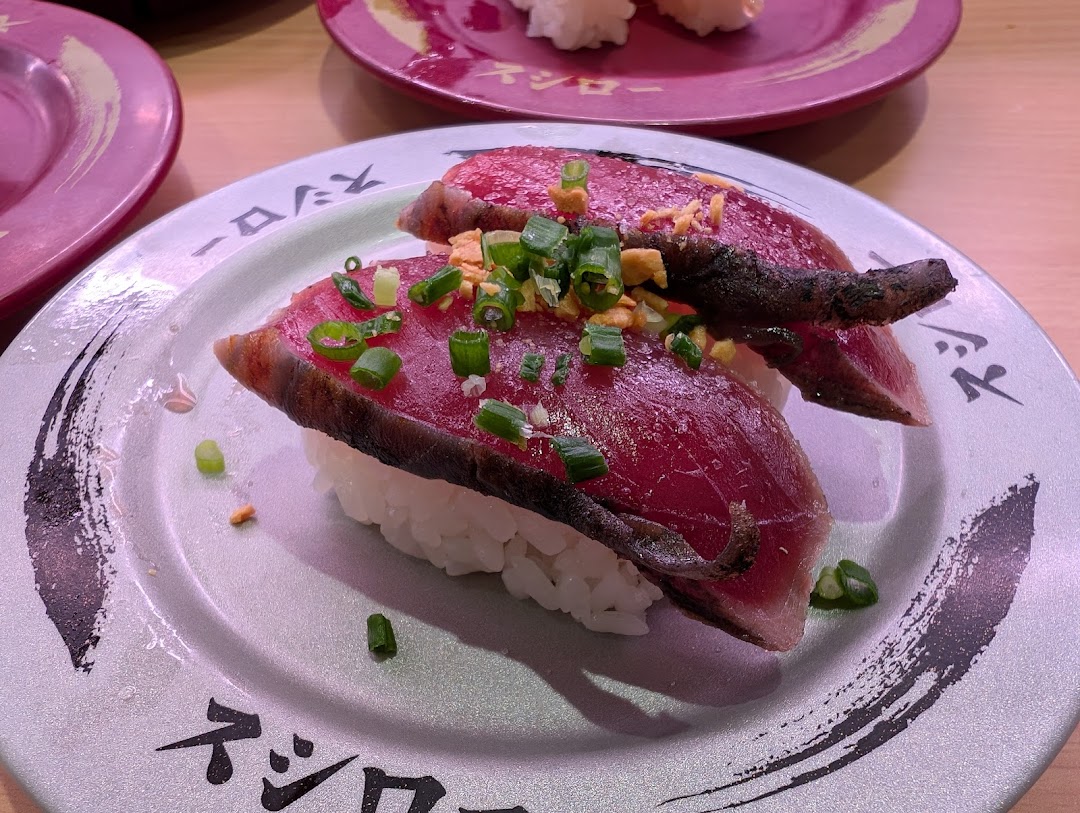 Close-up of seared tuna sushi on a plate, garnished with green onions.