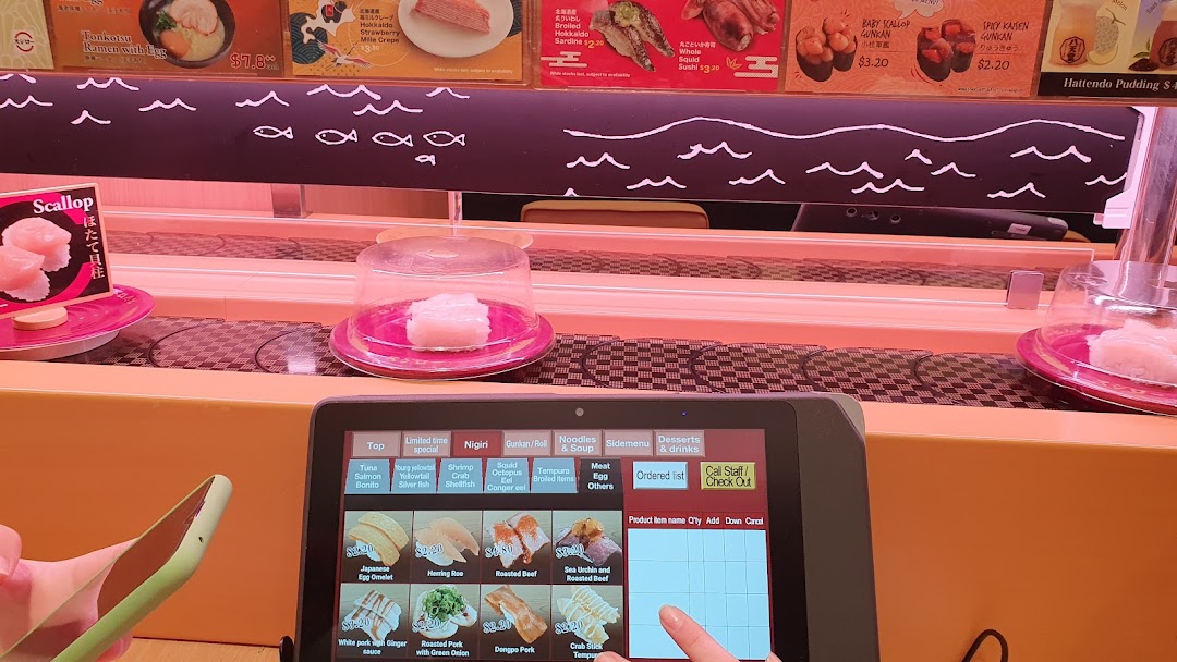 Sushi restaurant interior with conveyor belt and interactive ordering tablet.