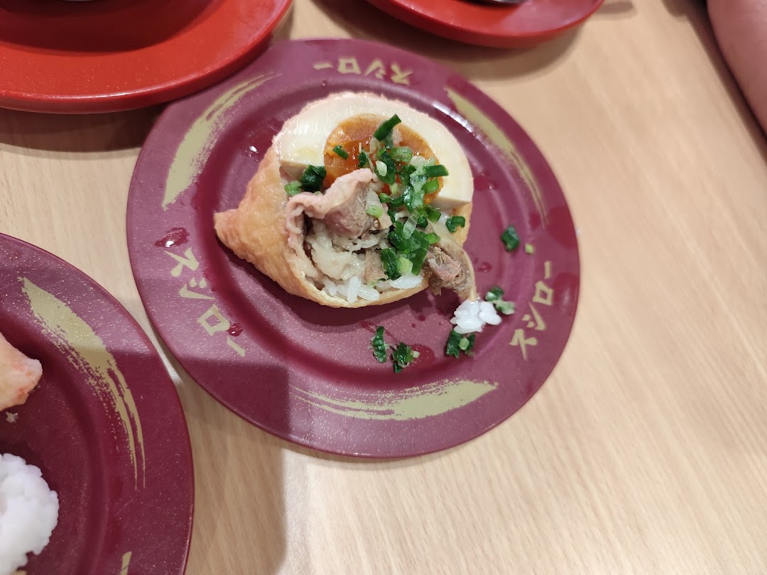 Close-up of a dish with meat, egg, and rice on a red plate.