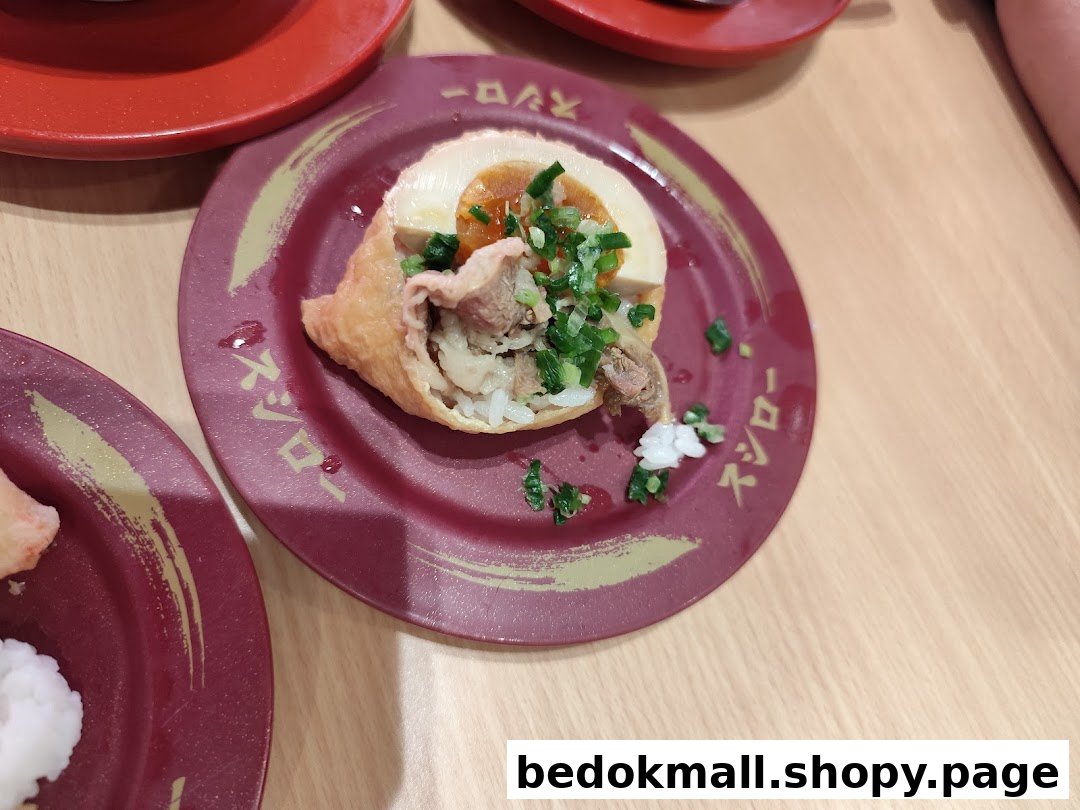 Close-up of a dish with meat, egg, and rice on a red plate.