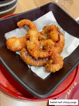 A black dish filled with golden-fried seafood, likely squid or octopus.
