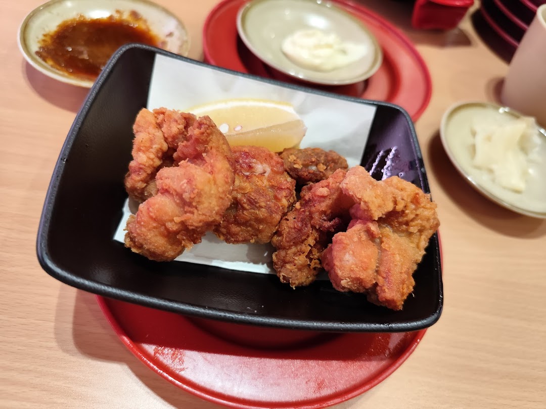 Fried chicken pieces with lemon in a black bowl on a table.
