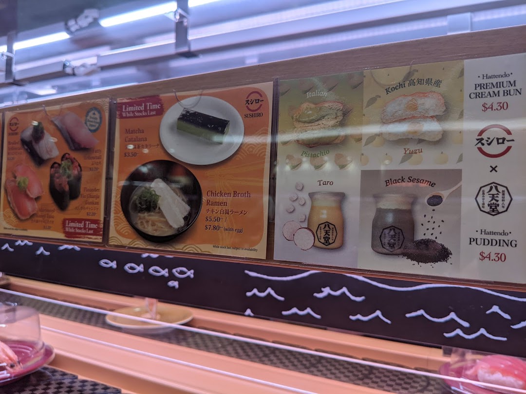 Menu panels showing sushi, ramen, desserts, and prices above a conveyor belt.