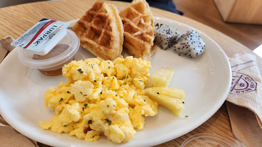 Plate with scrambled eggs, waffles, dragon fruit, and pineapple.