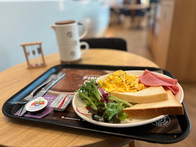 A breakfast meal with scrambled eggs, ham, toast, and salad on a tray.