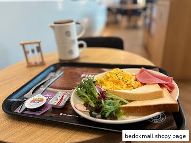 A breakfast meal with scrambled eggs, ham, toast, and salad on a tray.