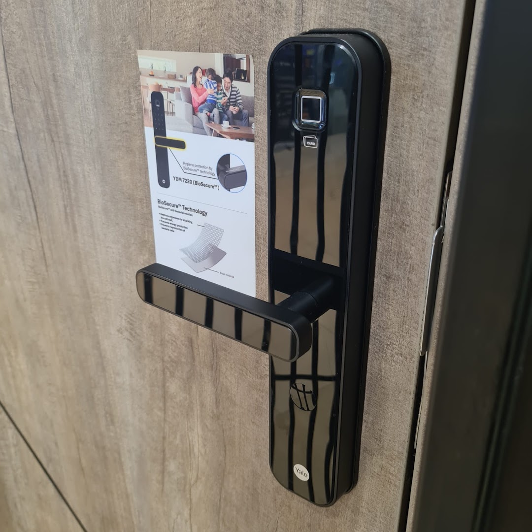 A black digital door lock with a product information sheet on a wooden display.