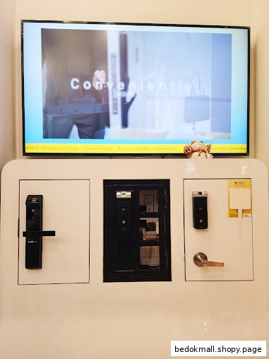 Display of door locks, handles, and a small door model with a screen above.