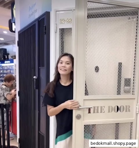 Woman stands by a display door in a retail shop.