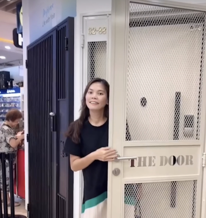 Woman standing by an open shop door displaying the name 'THE DOOR'.