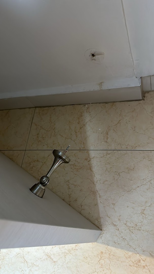 A light fixture hangs from a ceiling with a hole, above a tiled surface.