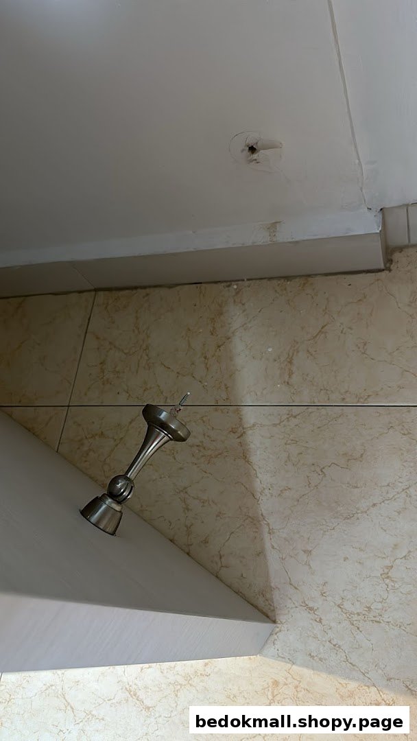 A light fixture hangs from a ceiling with a hole, above a tiled surface.