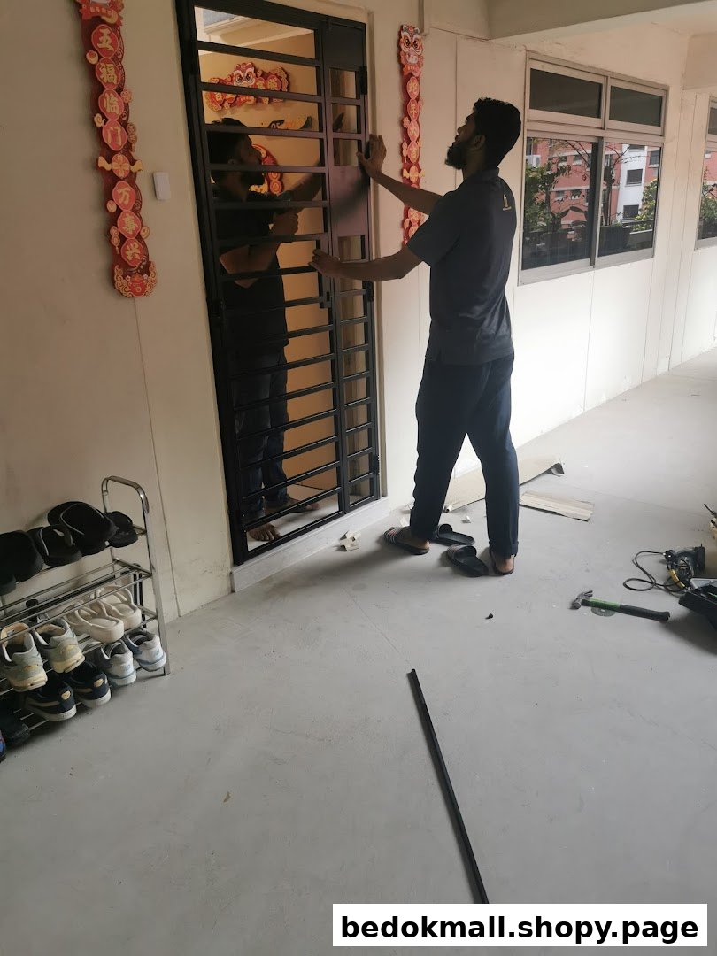 A person installing a metal gate/door with tools on the floor.