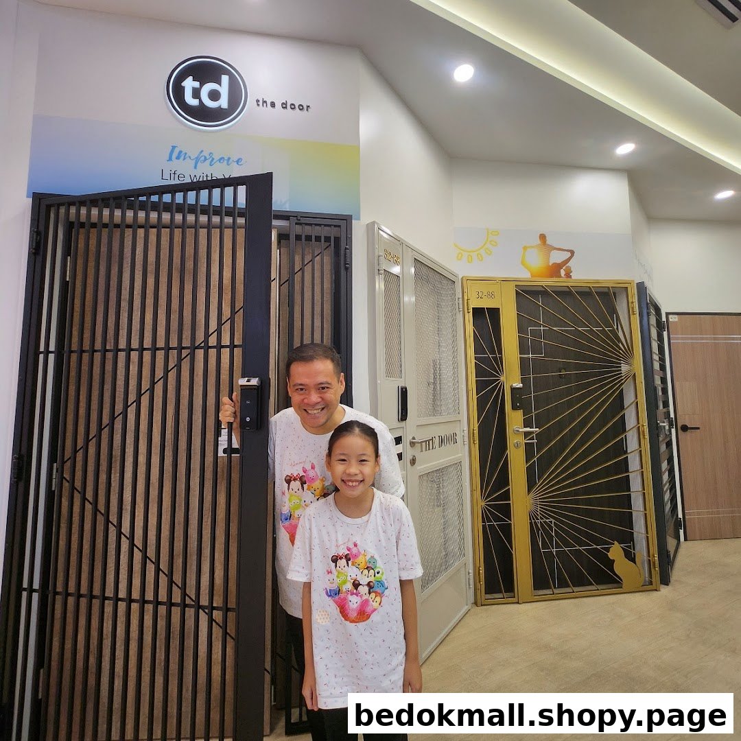 Two people smiling in a showroom displaying various doors and gates.