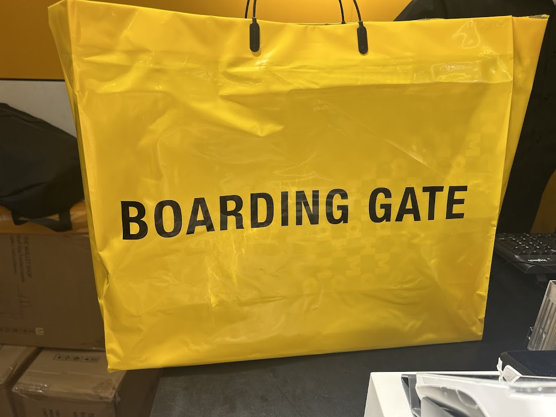 A large yellow shopping bag with 'BOARDING GATE' text on a counter.
