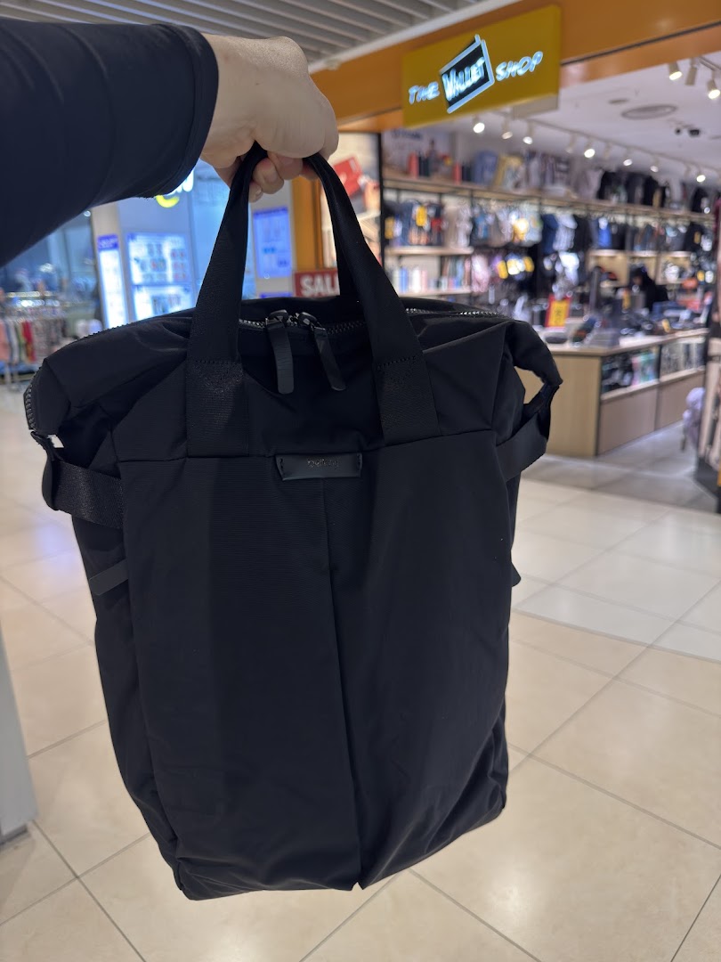 A person holds a black bag inside a retail shop with products on display.