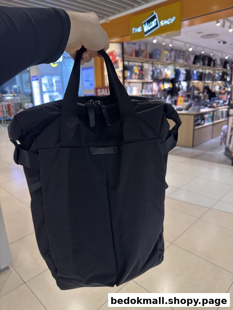 A person holds a black bag inside a retail shop with products on display.