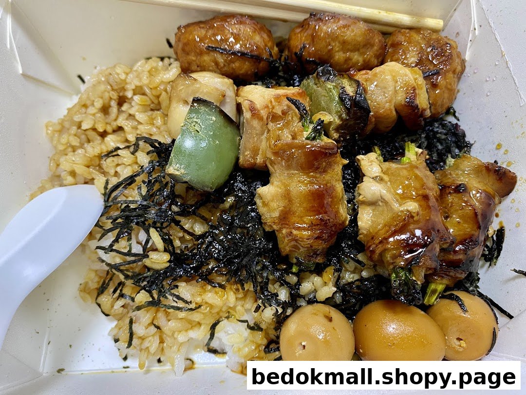 Close-up of a meal with rice, skewers, and eggs in a takeout box.
