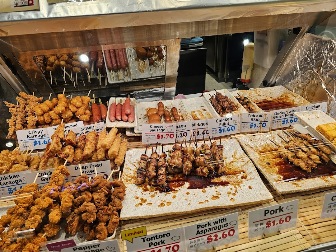 Display case filled with various skewered and fried food items with price tags.