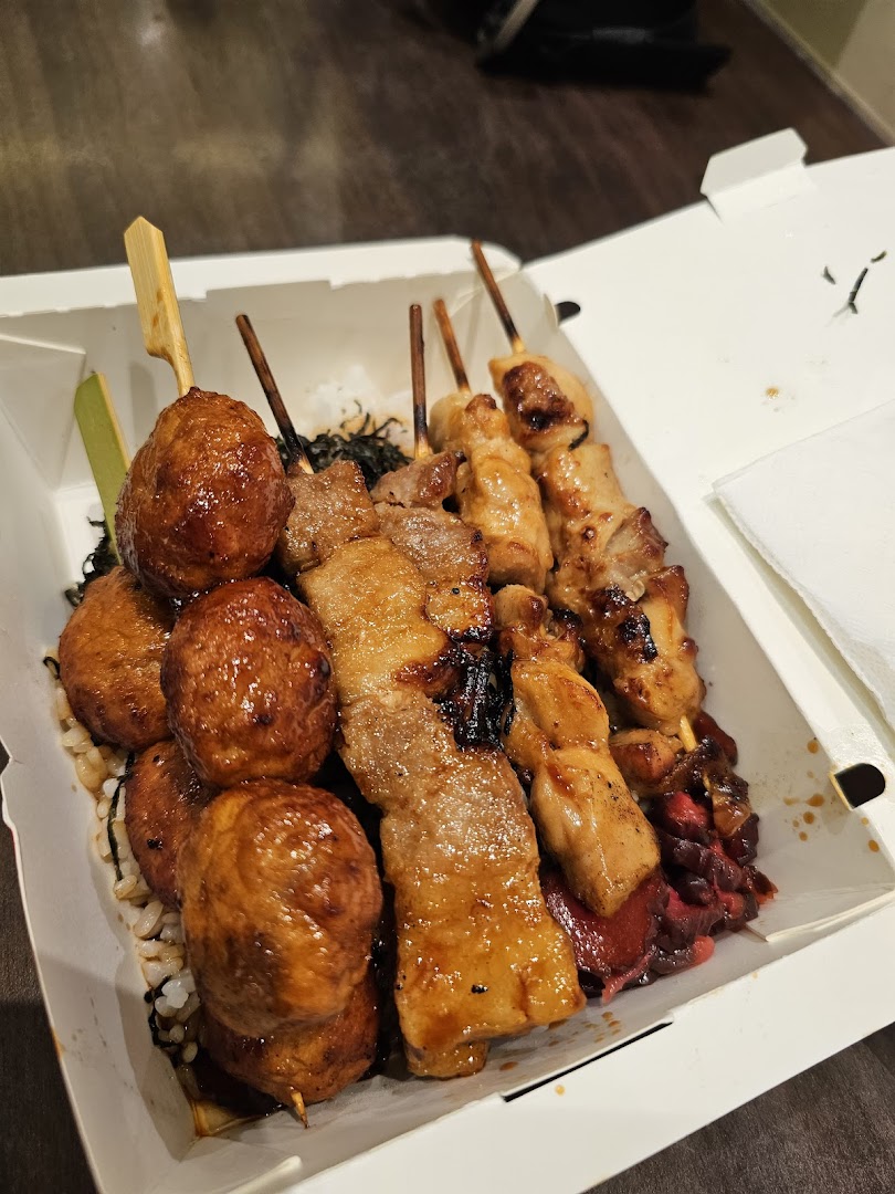 Takeaway box filled with various grilled meat skewers and rice.