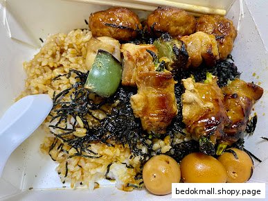 A box of rice with grilled skewers and eggs.