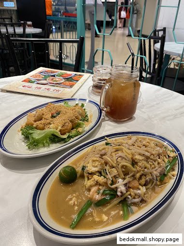 Two dishes, a drink, and a menu on a table in a restaurant setting.