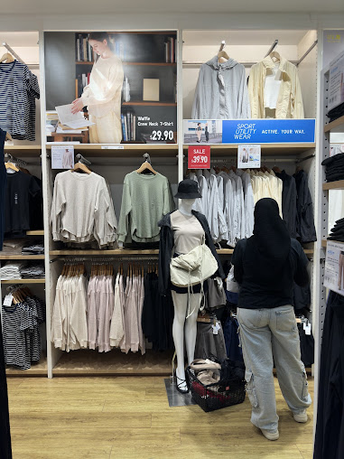 Interior view of a clothing store with racks, mannequins, and a customer.