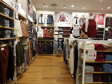 Retail store interior displaying clothing on racks, shelves, and mannequins.