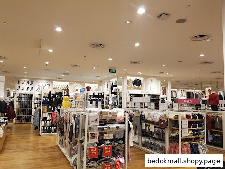 Interior view of a brightly lit clothing store with various apparel displays and mannequins.