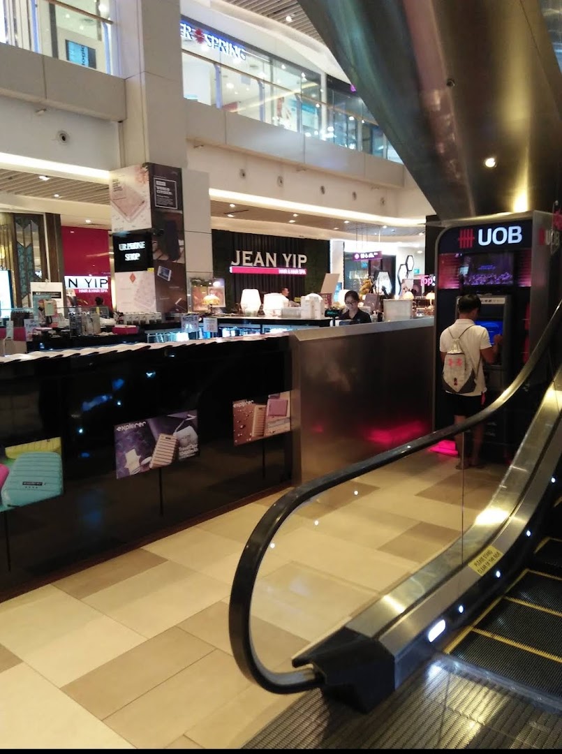 Mall interior with an ATM, escalator, and various shops.