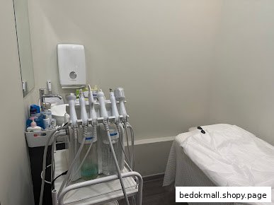 An interior treatment room with an aesthetic machine, sink, and bed.