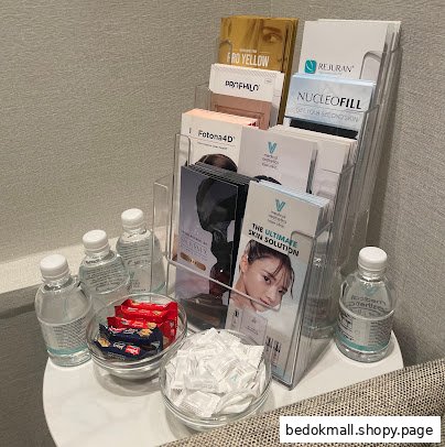Waiting area table with aesthetic clinic brochures, bottled water, and snacks.