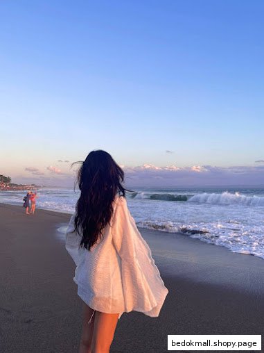 Rear view of a person on a beach watching waves at sunset.