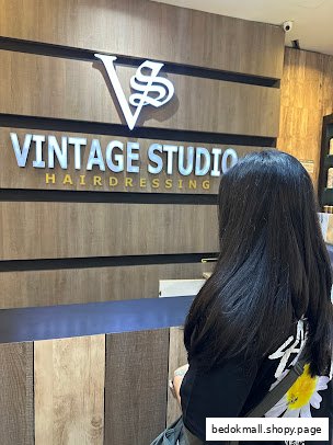 Person facing a reception counter with 'Vintage Studio Hairdressing' sign.
