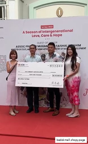 Four people holding a large check in front of an event banner.
