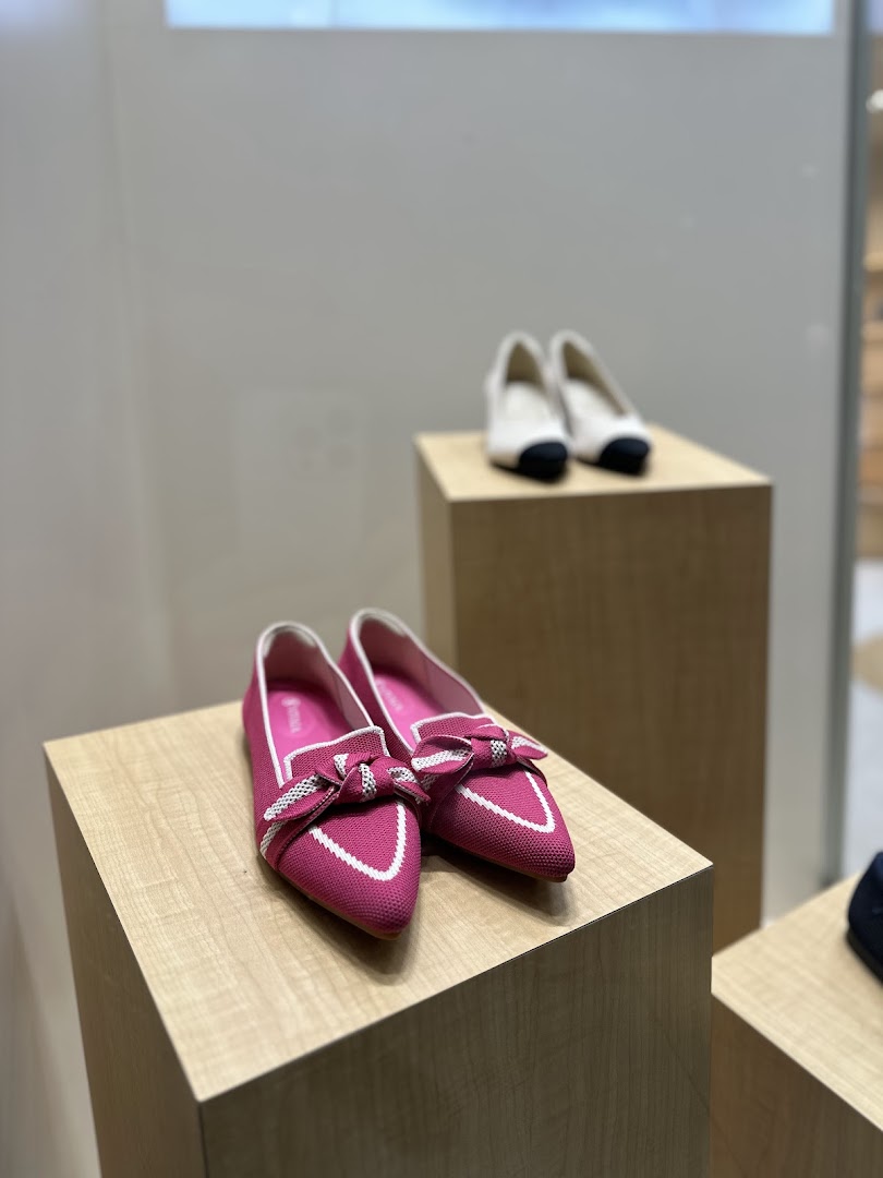 Pink and white shoes displayed on wooden pedestals inside a shop.