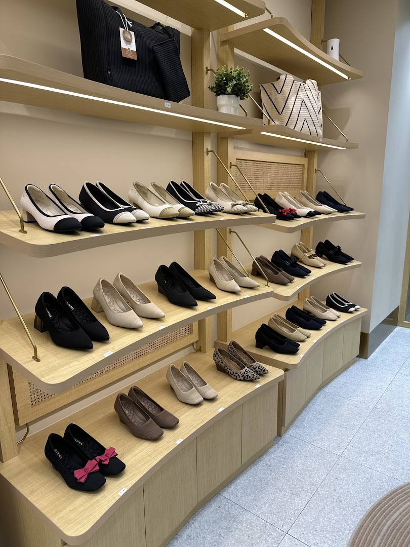 Interior view of a shoe shop with various shoes and bags on display shelves.