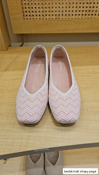 Pink and white chevron patterned shoes displayed on a wooden shelf.