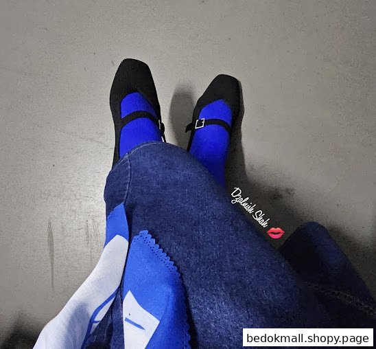 Person's legs wearing black shoes, blue socks, and blue jeans.