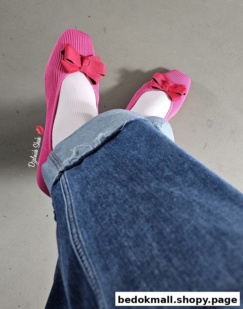 Person wearing pink shoes with bows, white socks, and blue jeans.