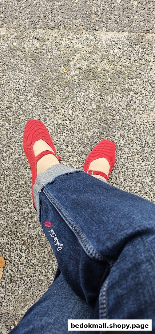 Person wearing blue jeans and red shoes on a textured ground.