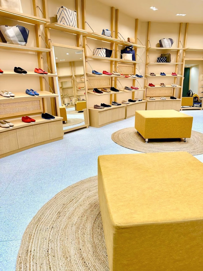 Interior view of a shoe and bag retail shop with display shelves and seating.